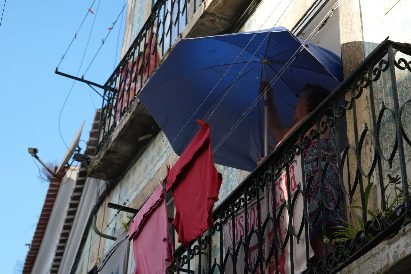 Kobieta na balkonie susząca parasol — miejska codzienność
