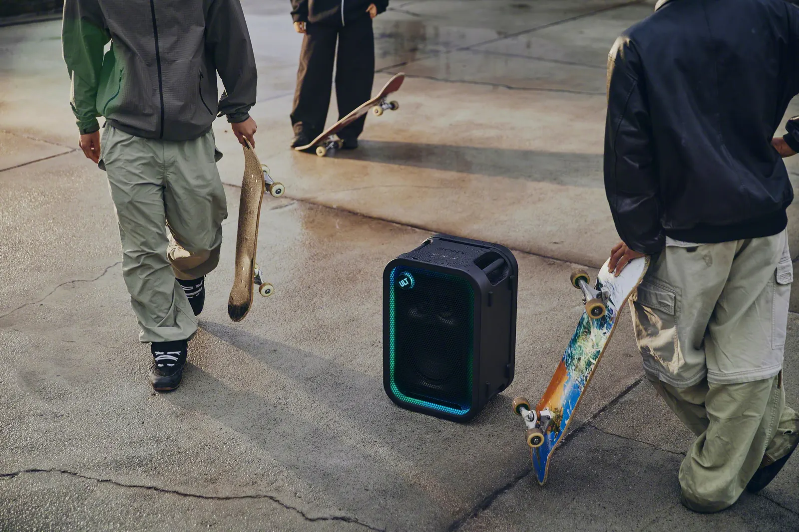 Dwoje skaterów z deskami obok ULT TOWER 5 na mokrym betonie